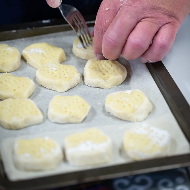 Whyte's Bakery shortbread Owner using a fork to shape shortbread on a baking tray lined with parchment paper.