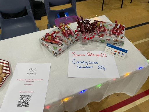Whyte's Bakery Christmas Market Table displaying candy canes, wrapped treats, and a sign promoting sweet samples.