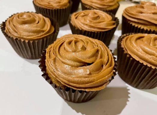 Whyte's Bakery Cupcakes Chocolate cupcakes with swirled chocolate frosting, arranged on a white surface.