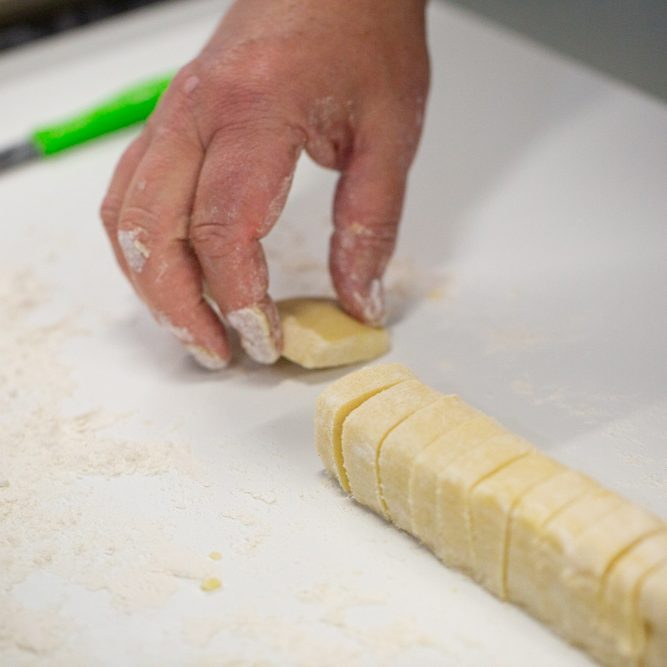 Whyte's bakery shortbread dough Owner cutting shortbread dough into small rectangular pieces on a floured surface.
